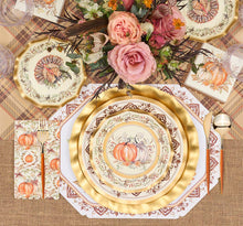 Load image into Gallery viewer, A fall-themed table setting features the Turkey & Gourds Table Setting Bundle by Sophistiplate LLC, including designer disposable plates adorned with turkey and gourd motifs, gold cutlery, plaid and burlap placemats, and a floral centerpiece with pink roses and autumnal blooms. The distinctive turkey design appears on both the top plate and matching napkin.