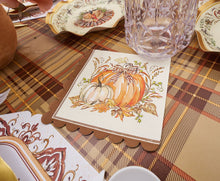 Load image into Gallery viewer, The Turkey & Gourds Table Setting Bundle by Sophistiplate LLC features festive napkins adorned with pumpkin illustrations and a bow, arranged on a plaid tablecloth alongside stylish disposable plates, a clear glass, and autumn-inspired tableware, creating a cozy Thanksgiving or fall-themed atmosphere.